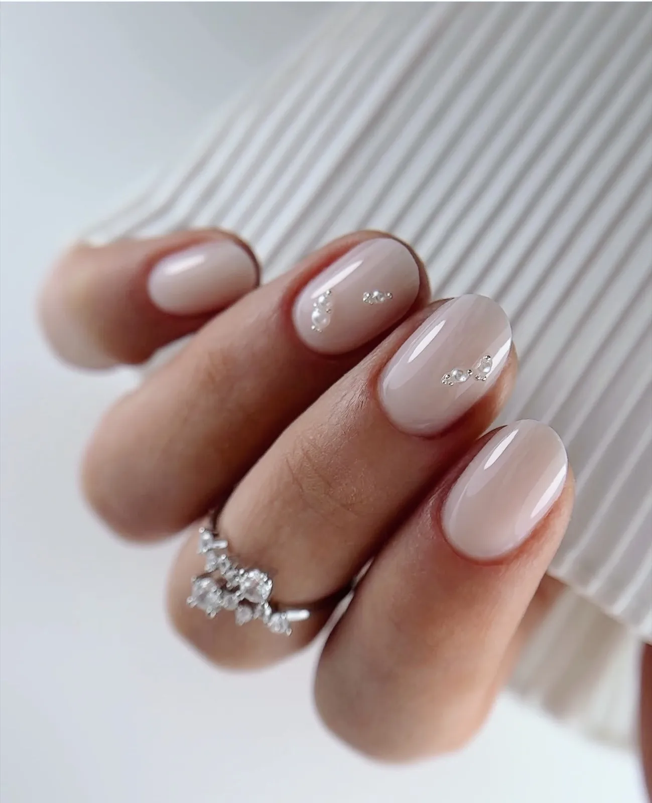 Ongles nude lactés ornés de micro-perles nacrées, réalisés à l'institut